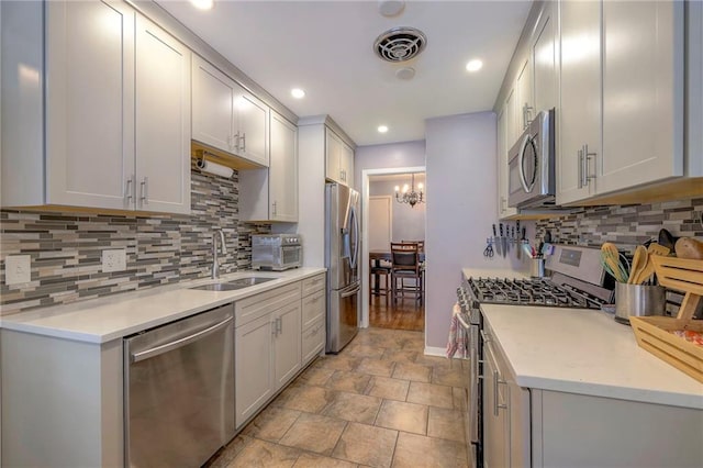 kitchen with stainless steel appliances, a chandelier, sink, and backsplash