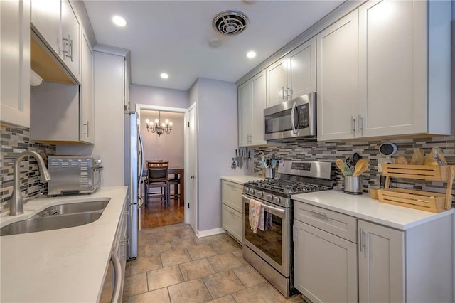 kitchen featuring tasteful backsplash, sink, a notable chandelier, light stone counters, and stainless steel appliances