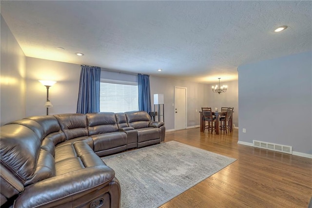 living room featuring hardwood / wood-style floors, a notable chandelier, and a textured ceiling