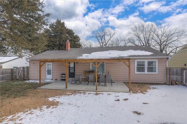 snow covered back of property with a patio area