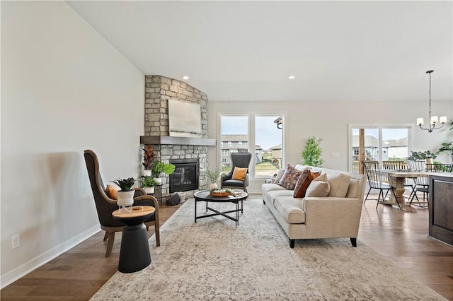 living room featuring a stone fireplace, hardwood / wood-style floors, and a chandelier