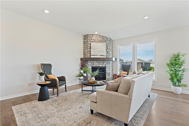 living room featuring a fireplace, light wood-type flooring, and vaulted ceiling