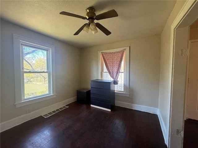 spare room with dark hardwood / wood-style floors, ceiling fan, and a wealth of natural light