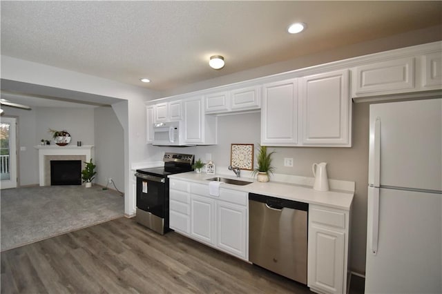 kitchen featuring appliances with stainless steel finishes, wood finished floors, light countertops, white cabinetry, and a sink