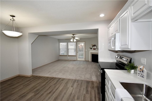 kitchen with stainless steel electric range oven, light countertops, white microwave, open floor plan, and white cabinetry