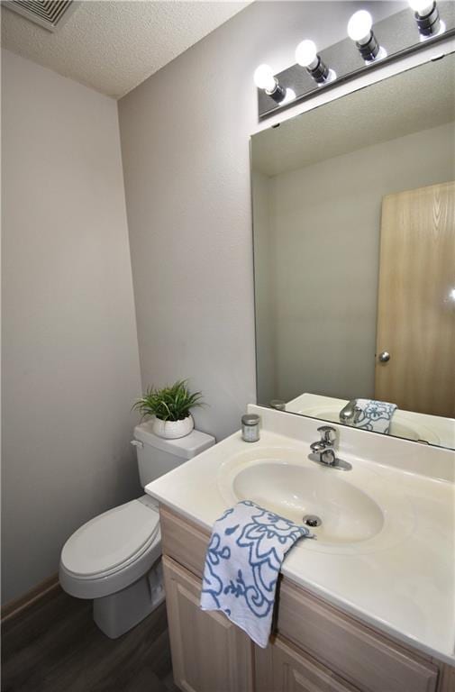 bathroom with visible vents, toilet, wood finished floors, a textured ceiling, and vanity