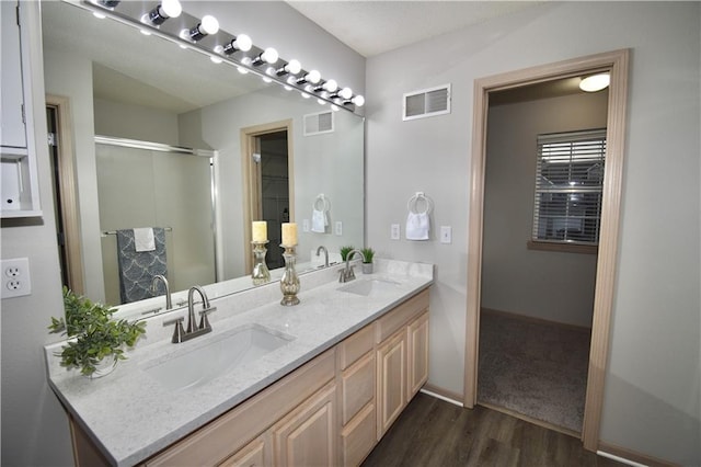 bathroom with double vanity, wood finished floors, a sink, and visible vents