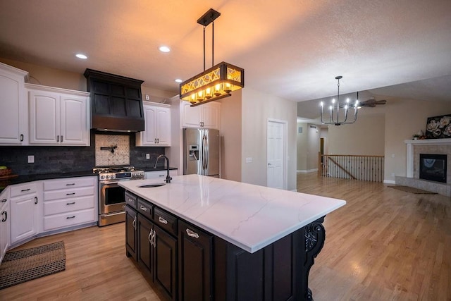 kitchen with sink, decorative light fixtures, white cabinetry, an island with sink, and appliances with stainless steel finishes