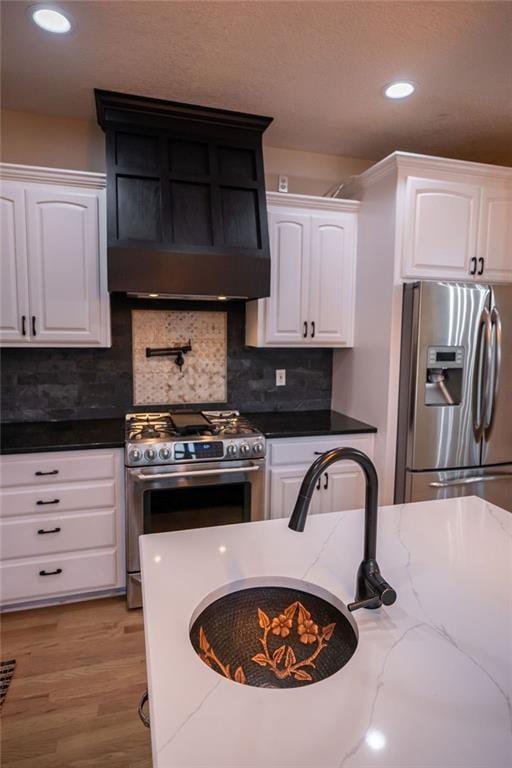 kitchen featuring appliances with stainless steel finishes, white cabinets, dark stone countertops, and tasteful backsplash