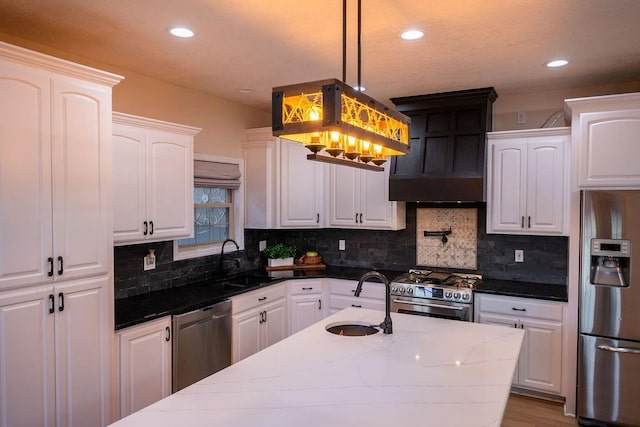 kitchen with stainless steel appliances, dark stone countertops, white cabinets, and sink