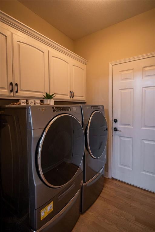 clothes washing area featuring independent washer and dryer, cabinets, and hardwood / wood-style flooring