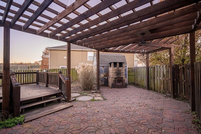 patio terrace at dusk featuring ceiling fan, a pergola, and a wooden deck