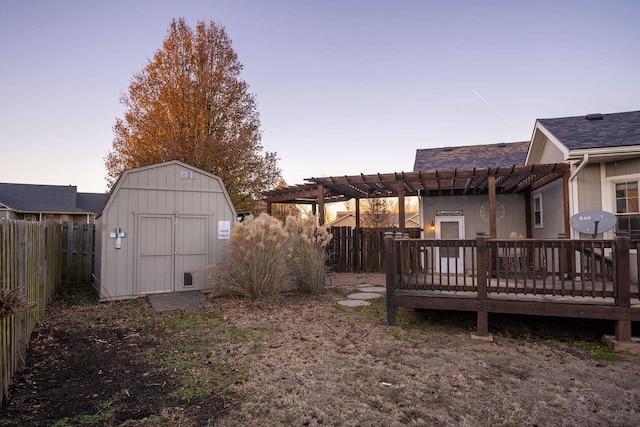 yard at dusk with a pergola, a wooden deck, and a storage unit