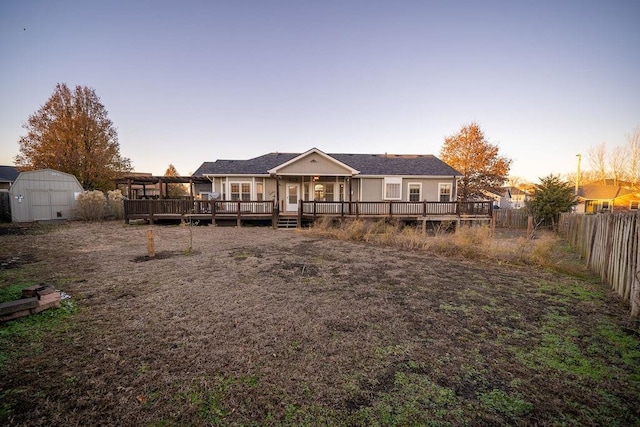 back house at dusk featuring a storage unit and a wooden deck