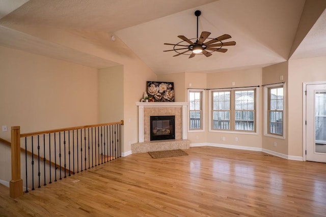 unfurnished living room with vaulted ceiling, a fireplace, ceiling fan, and light hardwood / wood-style floors