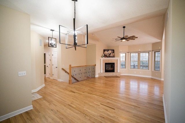 unfurnished living room with light wood-type flooring, lofted ceiling, and ceiling fan with notable chandelier