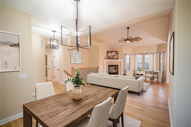 dining room with light hardwood / wood-style flooring, vaulted ceiling, and ceiling fan with notable chandelier