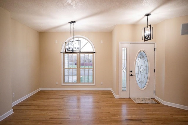 foyer featuring a textured ceiling, a notable chandelier, and hardwood / wood-style floors