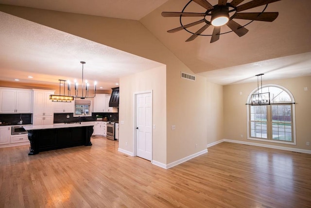 kitchen featuring white cabinets, stainless steel appliances, a kitchen island, and hanging light fixtures