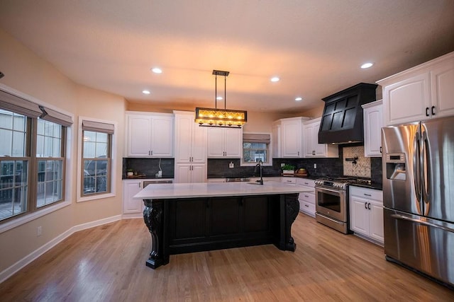 kitchen featuring white cabinets, stainless steel appliances, an island with sink, and pendant lighting