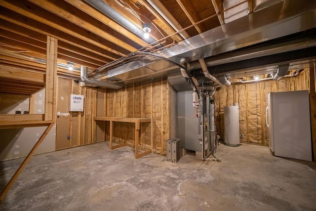 basement featuring white refrigerator, water heater, and heating unit