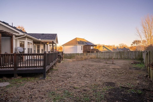 yard at dusk featuring a wooden deck