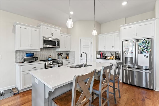 kitchen featuring dark wood-type flooring, sink, a breakfast bar area, white cabinetry, and stainless steel appliances