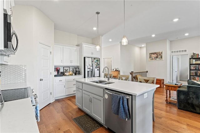 kitchen with pendant lighting, a center island with sink, sink, white cabinetry, and stainless steel appliances