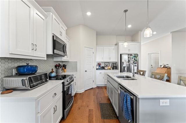 kitchen featuring white cabinetry, stainless steel appliances, backsplash, an island with sink, and pendant lighting