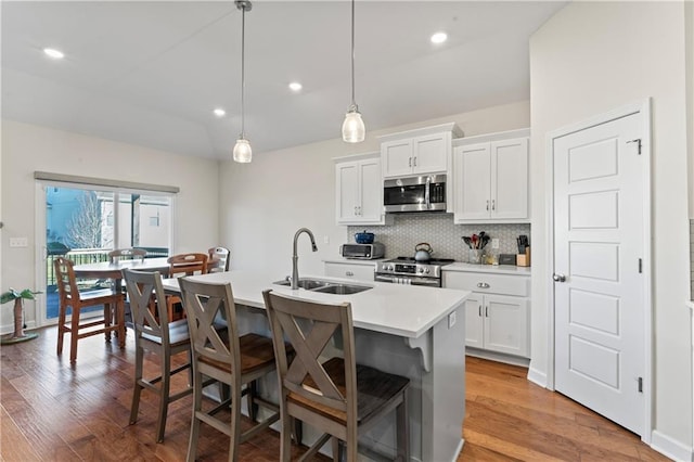 kitchen with sink, white cabinets, hanging light fixtures, and appliances with stainless steel finishes