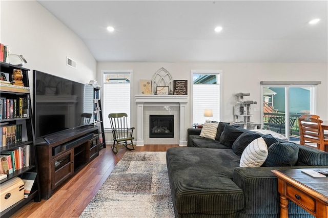 living room with light wood-type flooring, a wealth of natural light, and vaulted ceiling