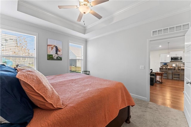 bedroom featuring hardwood / wood-style flooring, ceiling fan, crown molding, and a tray ceiling