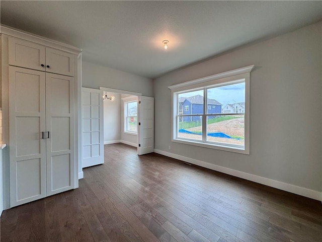 7601 NE 103rd Ter, Kansas City, MO 64157 - unfurnished bedroom with baseboards, dark wood-style flooring, and a chandelier