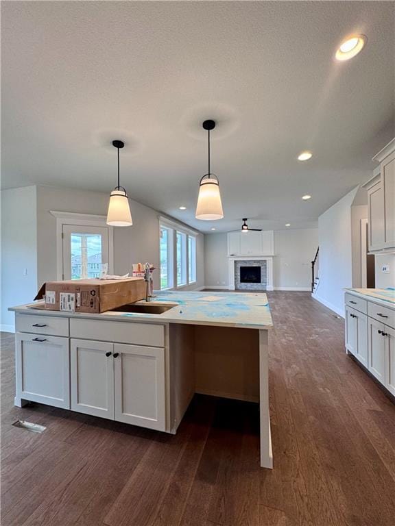 7601 NE 103rd Ter, Kansas City, MO 64157 - kitchen with open floor plan, dark wood-style flooring, a sink, hanging light fixtures, and white cabinetry