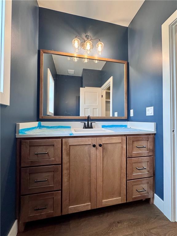 7601 NE 103rd Ter, Kansas City, MO 64157 - bathroom featuring baseboards, vanity, and wood finished floors