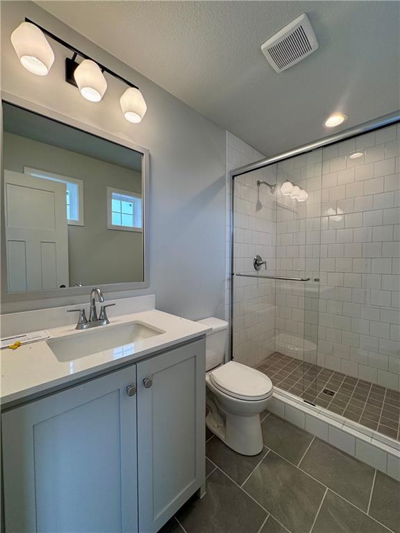 7601 NE 103rd Ter, Kansas City, MO 64157 - full bathroom featuring tile patterned flooring, a stall shower, toilet, vanity, and a textured ceiling