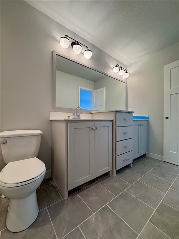 7601 NE 103rd Ter, Kansas City, MO 64157 - bathroom featuring vanity, toilet, tile patterned flooring, a textured ceiling, and baseboards