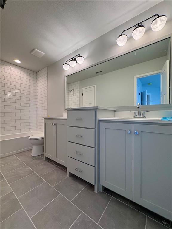 7601 NE 103rd Ter, Kansas City, MO 64157 - full bath with tile patterned flooring, vanity, toilet, shower / bathtub combination, and a textured ceiling