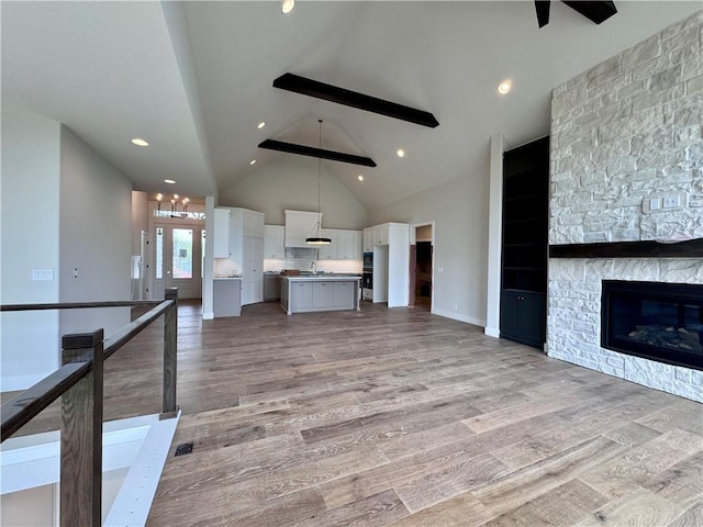 7719 NE 103rd Ter, Kansas City, MO 64157 - unfurnished living room with high vaulted ceiling, ceiling fan, light wood-style floors, a fireplace, and a sink