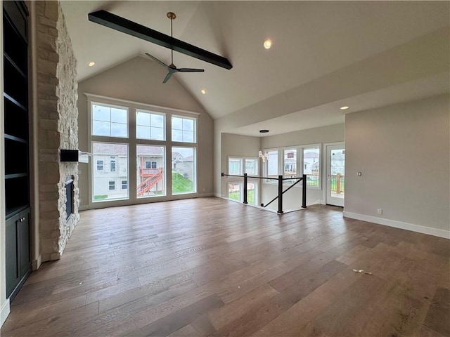 7719 NE 103rd Ter, Kansas City, MO 64157 - unfurnished living room with a ceiling fan, a stone fireplace, plenty of natural light, hardwood / wood-style floors, and high vaulted ceiling