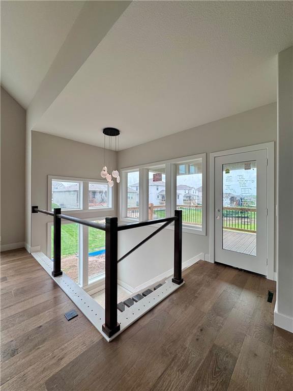 7719 NE 103rd Ter, Kansas City, MO 64157 - hallway with an upstairs landing, baseboards, wood finished floors, and a chandelier