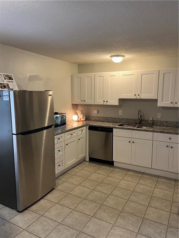 kitchen with white cabinetry, sink, dark stone counters, a textured ceiling, and appliances with stainless steel finishes