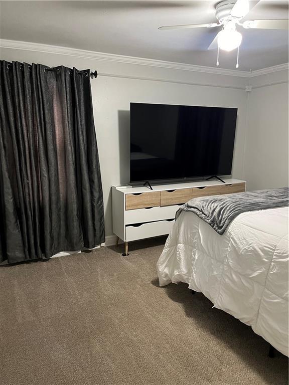 carpeted bedroom with ceiling fan and crown molding