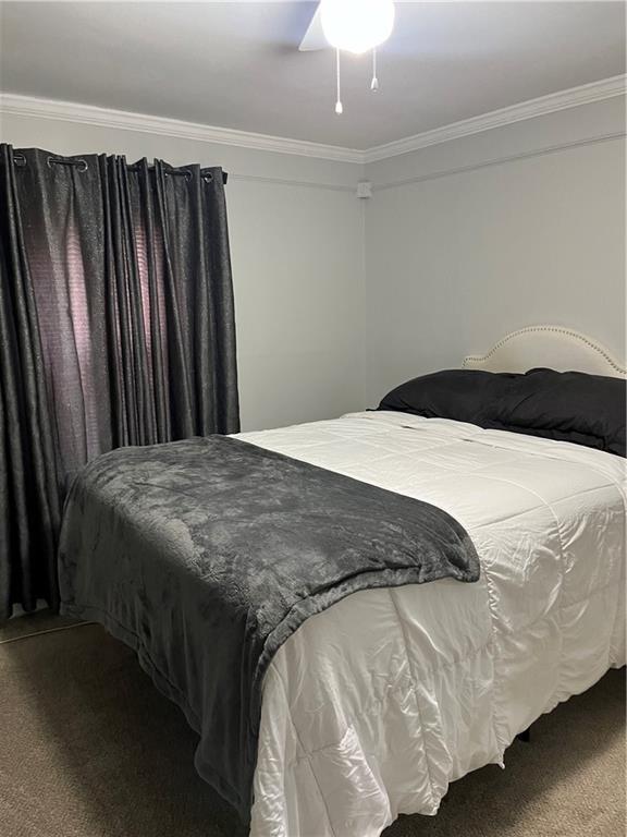 carpeted bedroom featuring ceiling fan and ornamental molding