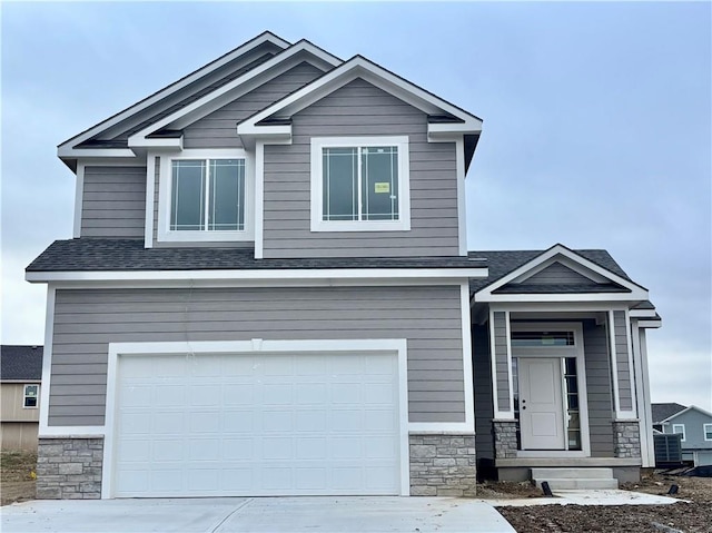 craftsman house featuring a garage, stone siding, driveway, and a shingled roof