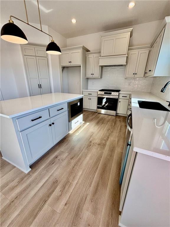 kitchen with pendant lighting, light countertops, gas stove, white cabinets, and built in microwave