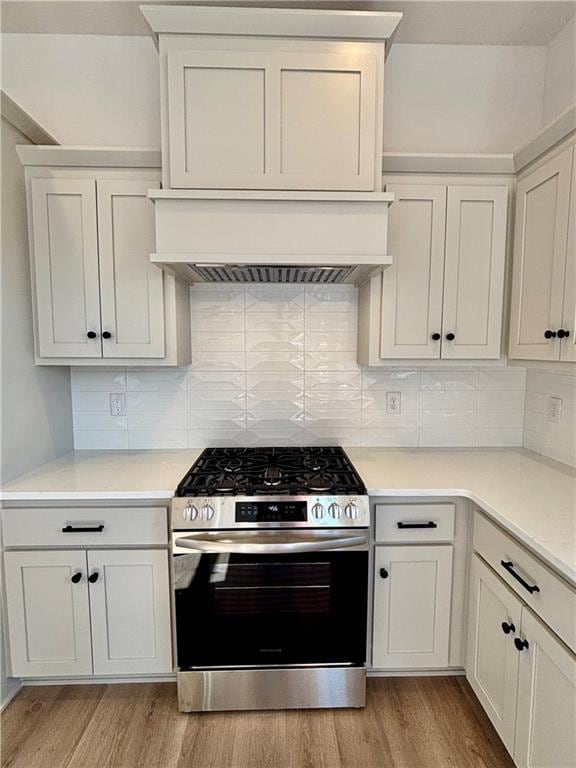 kitchen featuring premium range hood, light countertops, stainless steel range with gas stovetop, and light wood-style flooring