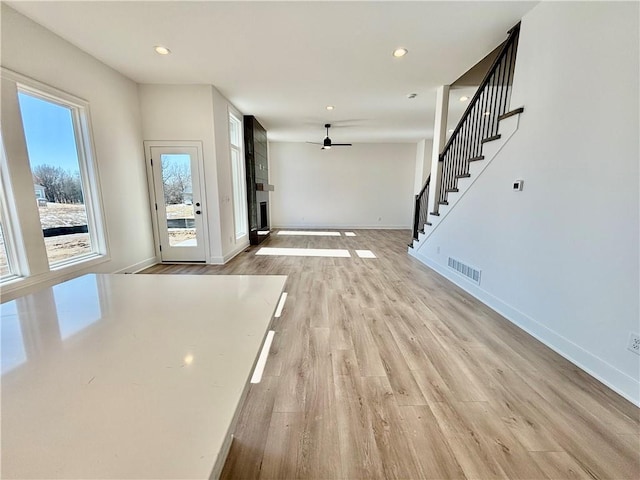 foyer entrance with stairs, light wood finished floors, visible vents, and baseboards