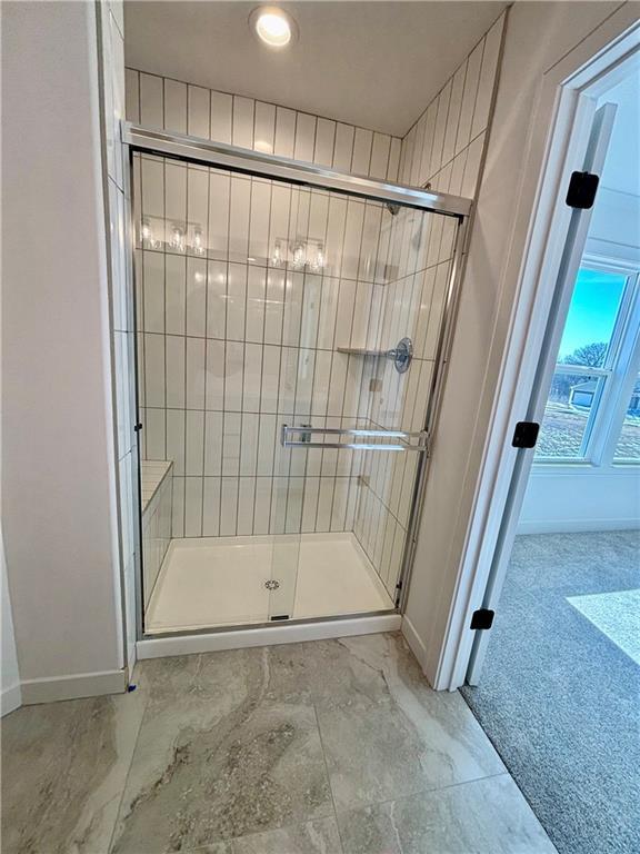 full bath featuring a shower stall and baseboards