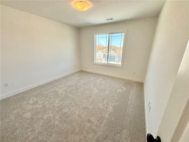 carpeted empty room with visible vents, a textured ceiling, and baseboards